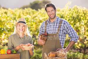 Smiling farmer couple holding chicken and eggs