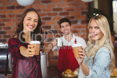 Smiling waiter and two customers looking at the camera