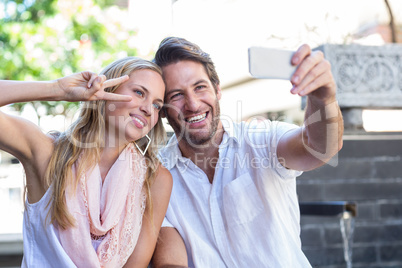 Smiling couple sitting and taking selfies