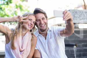 Smiling couple sitting and taking selfies