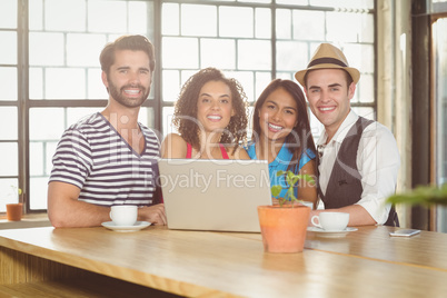 Smiling friends standing around laptop