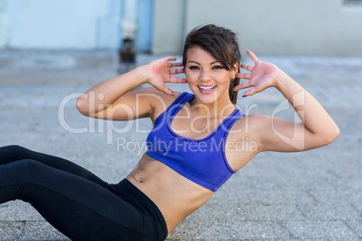 Portrait of smiling athletic woman doing sit-ups