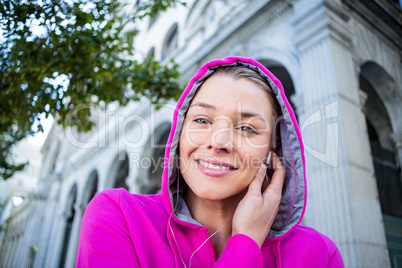 Portrait of a woman wearing a pink jacket putting her headphones