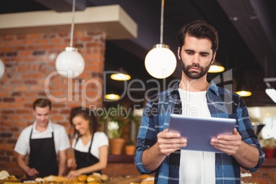 Concentrated hipster using tablet in front of working barista