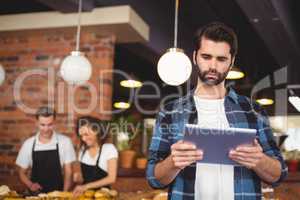 Concentrated hipster using tablet in front of working barista