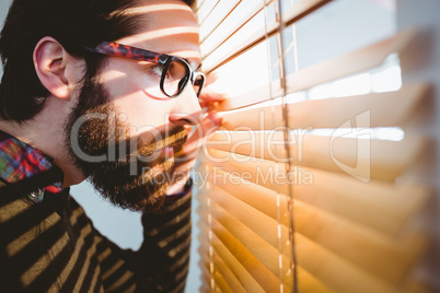 Hipster businessman peeking through blinds