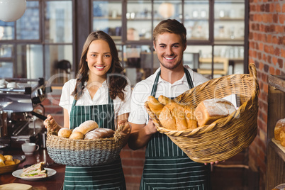 Smiling co-workers holding breads basket