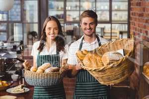 Smiling co-workers holding breads basket