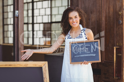 Smiling waitress showing chalkboard with open sign