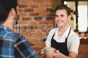 Smiling barista giving coffee to customer