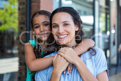 Portrait of a smiling mother and her daughter piggybacking