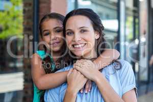 Portrait of a smiling mother and her daughter piggybacking