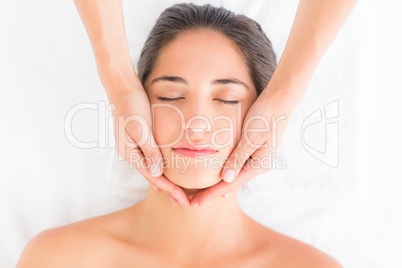 Attractive young woman receiving head massage at spa center