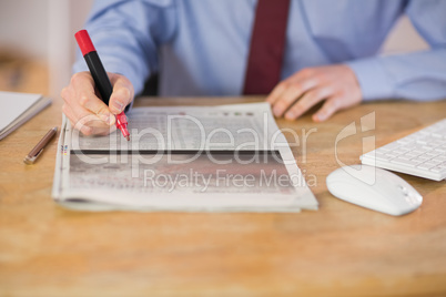 Businessman marking the newspaper with marker