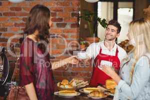 Smiling waiter serving a coffee to a customer