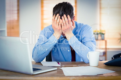 Stressed businessman with head in hands