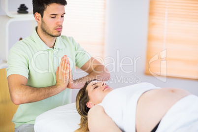 Relaxed pregnant woman getting reiki treatment