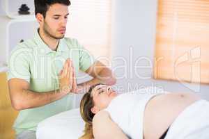 Relaxed pregnant woman getting reiki treatment