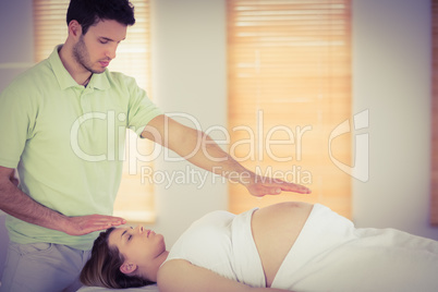 Relaxed pregnant woman getting reiki treatment