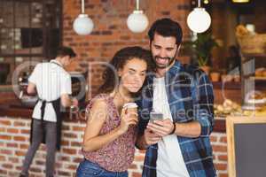 Smiling hipster couple looking at smartphone