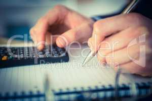 Businessman using a calculator and writing