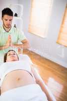 Relaxed pregnant woman getting reiki treatment