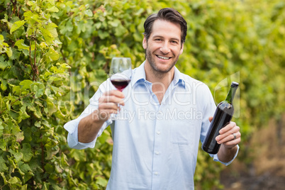 Young happy man smiling at camera and holding a glass of wine