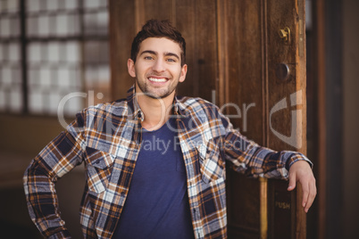 Smiling casual waiter leaning against door