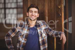 Smiling casual waiter leaning against door
