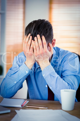 Stressed businessman with head in hands