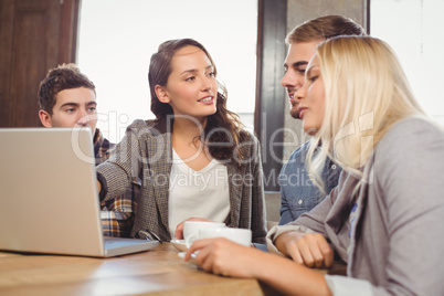 Friends discussing and pointing on laptop screen