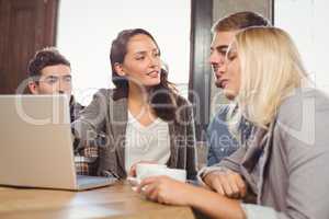 Friends discussing and pointing on laptop screen