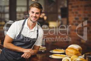Handsome waiter leaning on a food table