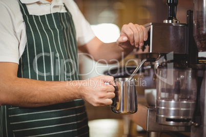 Barista steaming milk at the coffee machine