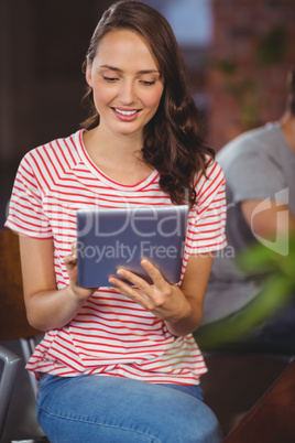 Smiling woman sitting and using tablet computer Smiling woman sitting and using tablet computer