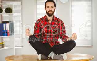 Hipster businessman meditating at his desk