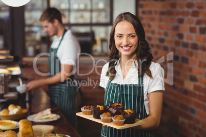 Pretty waitress holding a tray of muffins