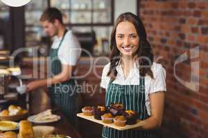 Pretty waitress holding a tray of muffins