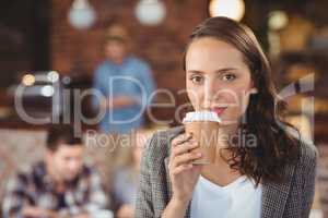 Smiling young woman drinking from take-away cup