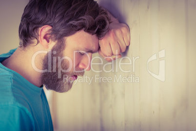 Troubled hipster leaning against wall