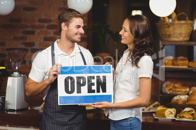 Smiling team posing with open sign