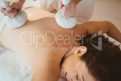 Young woman getting herbal compress massage
