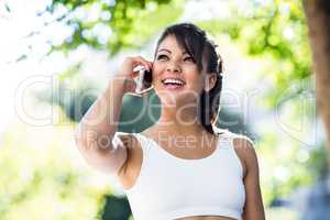 Smiling athletic woman phoning with smartphone