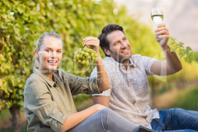 Two young happy vintners holding a glass of wine and grapes