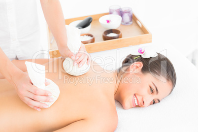 Beautiful brunette enjoying a herbal compress massage