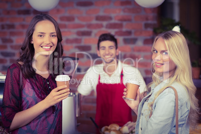 Smiling waiter and two customers looking at the camera