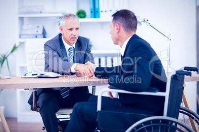 Businessman in wheelchair speaking with colleague Businessman in wheelchair speaking with colleague