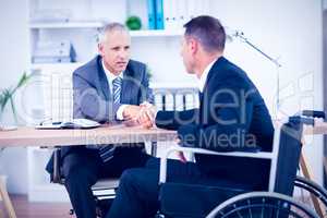 Businessman in wheelchair speaking with colleague