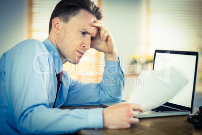 Focused businessman reading document at desk