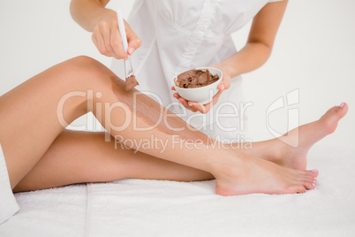 Therapist waxing womans leg at spa center